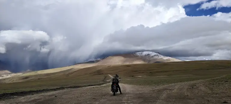 A motorcycle rider crossing a remote high-altitude Himalayan road